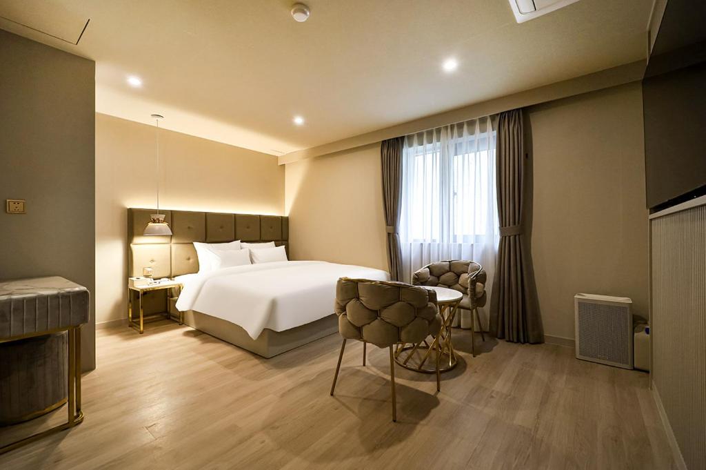 Habitación de hotel con cama, mesa y sillas en Denbasta Hotel Daeyeon en Busan