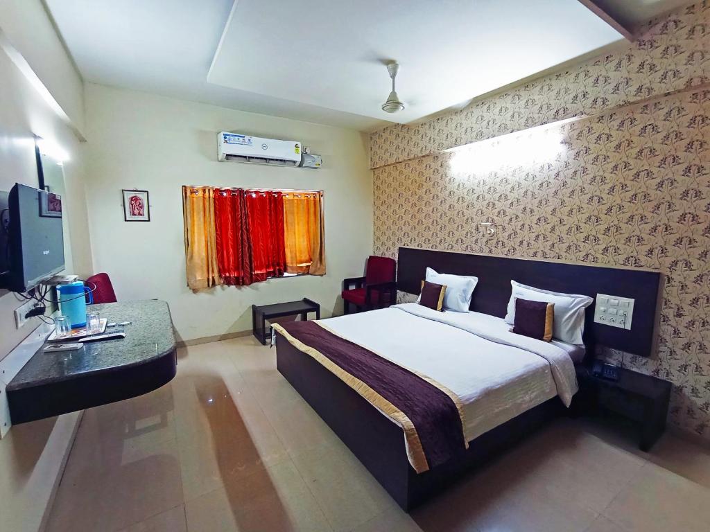 a bedroom with a bed and a desk and a television at Anjaneya Residency in Belgaum