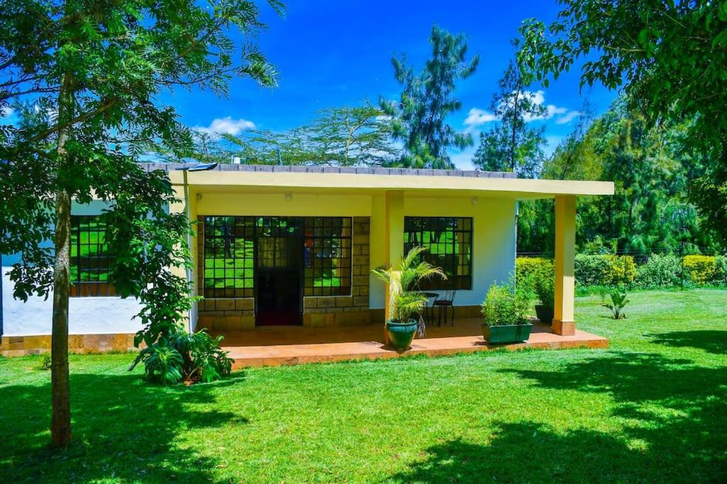 a small yellow house with a green yard at Gatville Serene Gardens in Kiserian