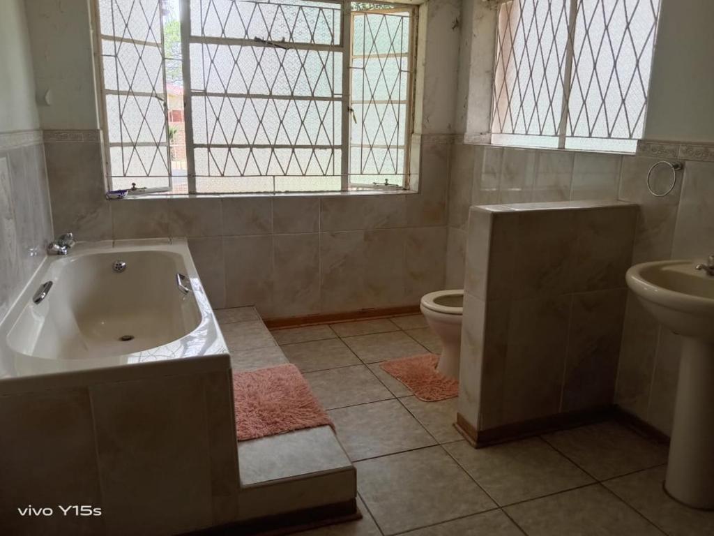 a bathroom with a tub and a toilet and a sink at Bullez guest house in Mahikeng