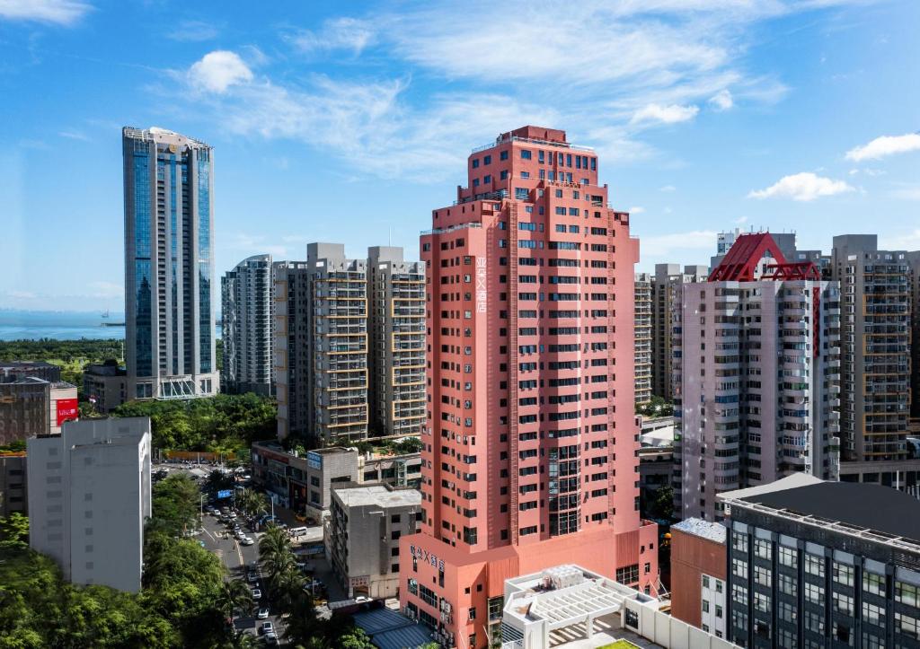 a tall red building in the middle of a city at Atour X Hotel Haikou International Trade Center in Haikou