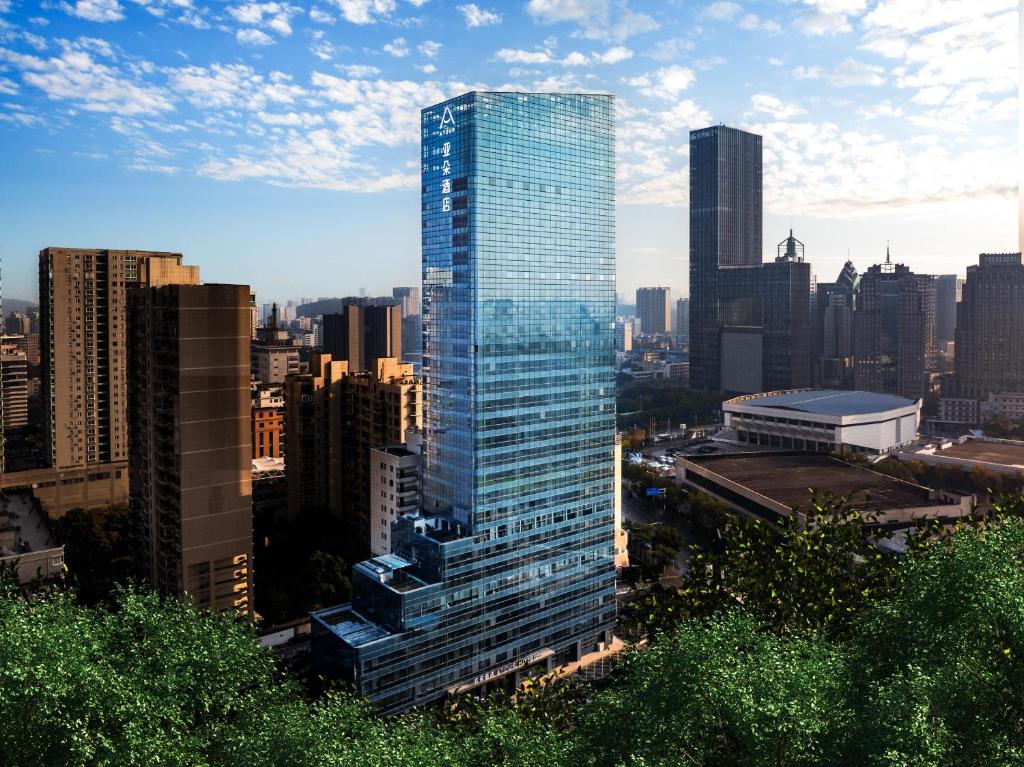 a tall glass building in a city at Atour Hotel Wuhan Chuhe Han Street Hongshan Plaza in Wuhan