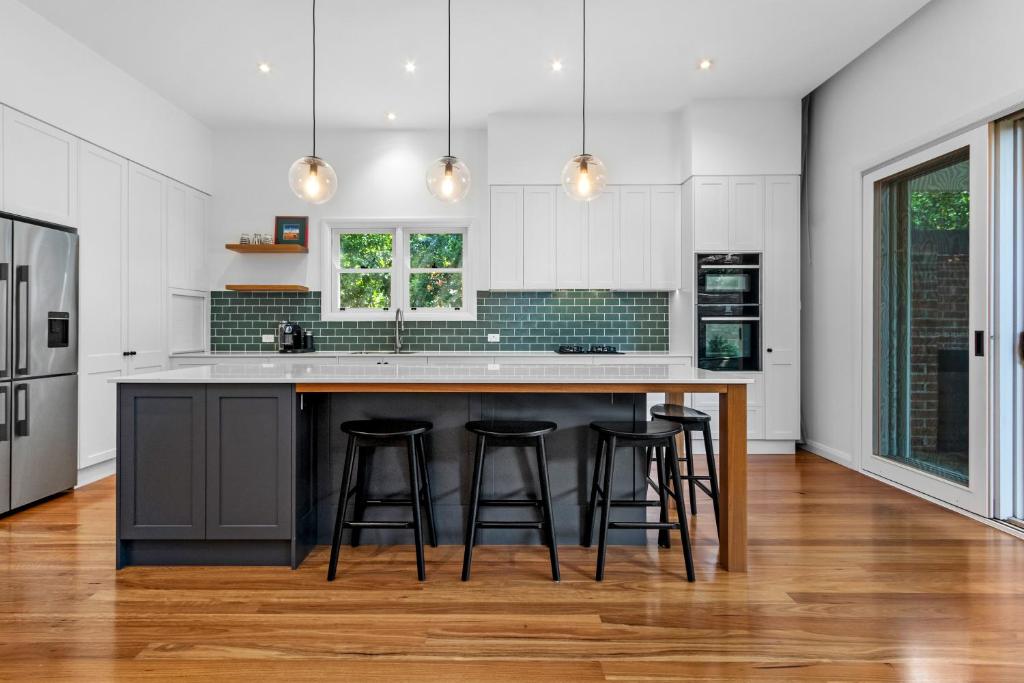 a kitchen with a large island with bar stools at Pure Elegance in Cooks Hill in Newcastle