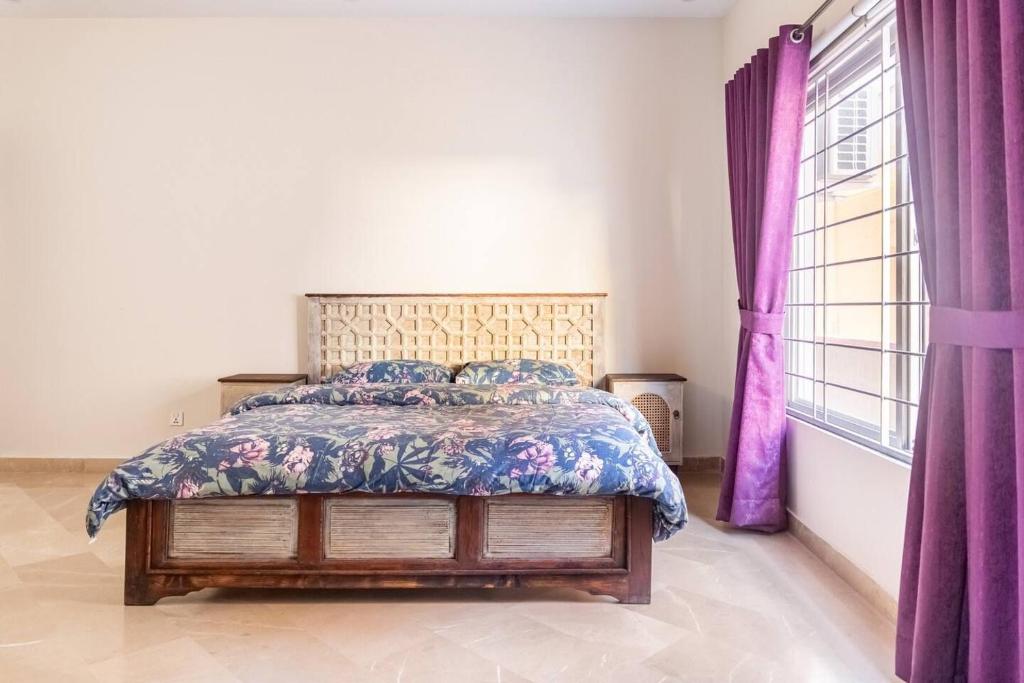 Schlafzimmer mit einem Bett und lila Vorhängen in der Unterkunft Cielo in Islamabad