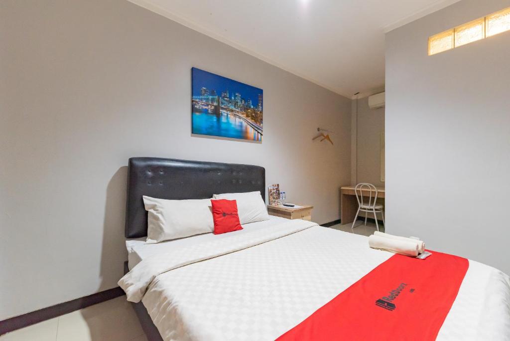 um quarto com uma cama com um cobertor vermelho em RedDoorz near Botani Square Mall em Bogor