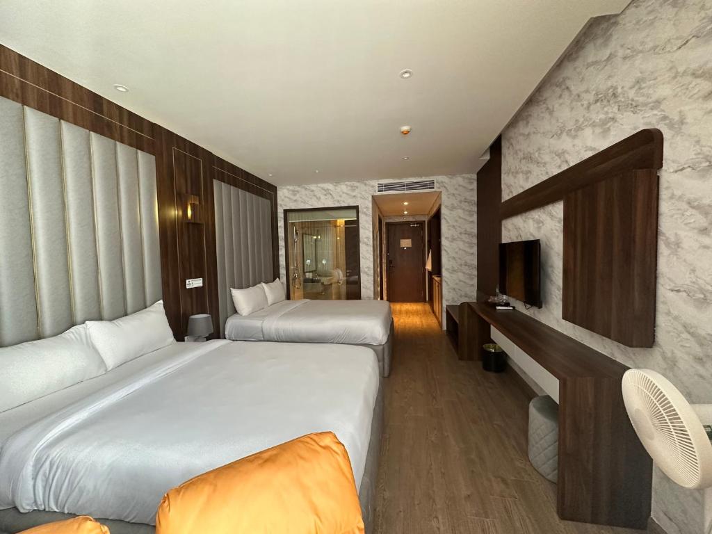a hotel room with two beds and a television at Apec Mandala Mui Ne Phan Thiet in Ấp Long Sơn