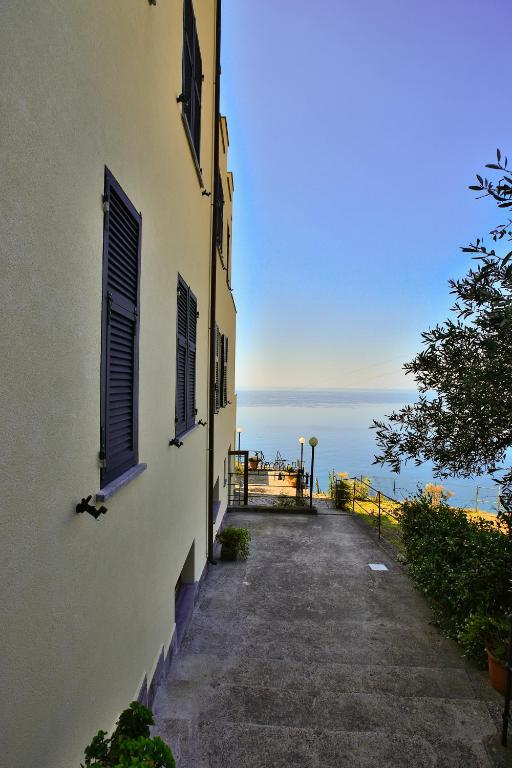 a building with a pathway next to the ocean at Albergo Luna di Marzo in Volastra