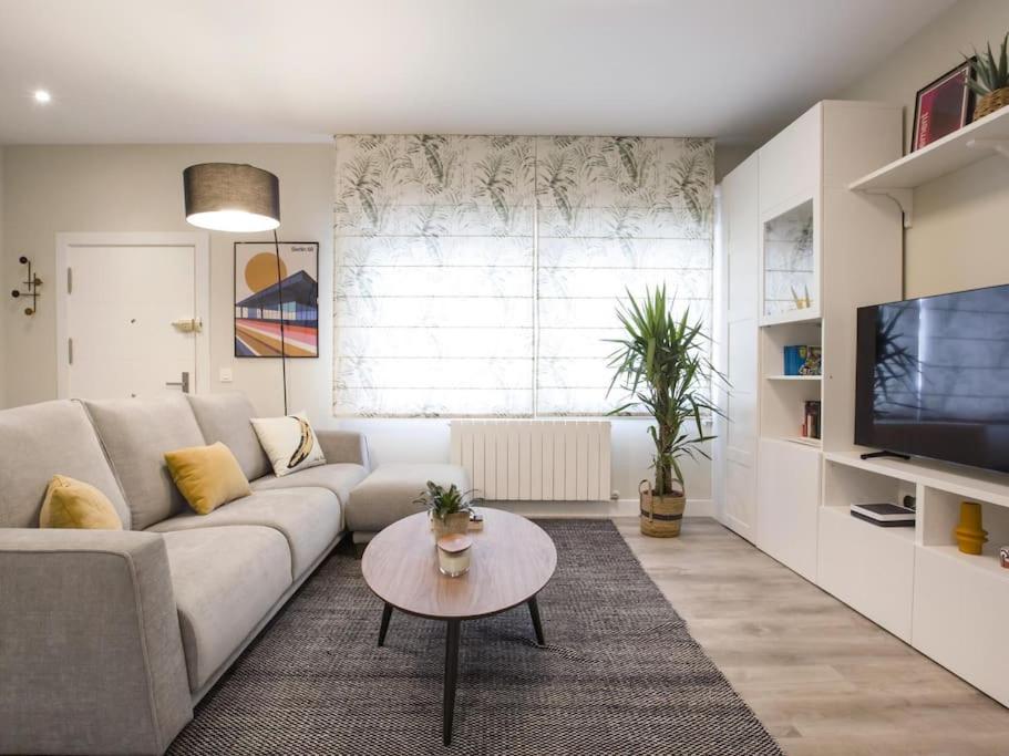 ein Wohnzimmer mit einem weißen Sofa und einem TV in der Unterkunft Bilbao Costa III by Aston Rentals in Getxo