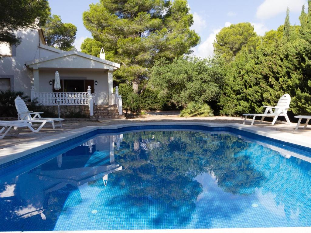 una piscina con 2 sillas y una casa en INNOUTHOME GRAN CASA CON PISCINA Virgen Cinta, en L'Ametlla de Mar