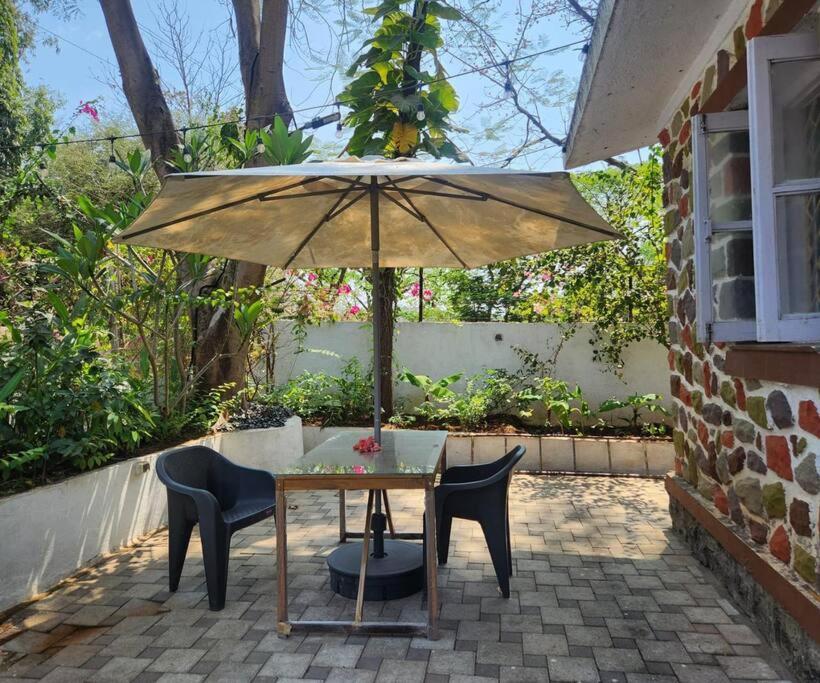 a table with chairs and an umbrella on a patio at BnBBuddy- Great Escape@Karjat, Maharashtra in Karjat