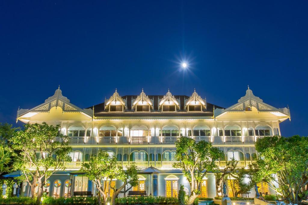 a large building at night with the moon above it at At Pingnakorn Riverside in Chiang Mai