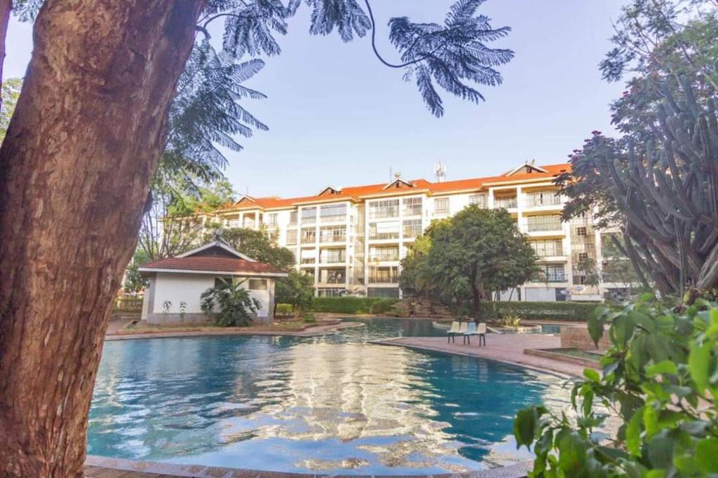 a hotel with a swimming pool in front of a building at JCA APARTMENTS in Nairobi