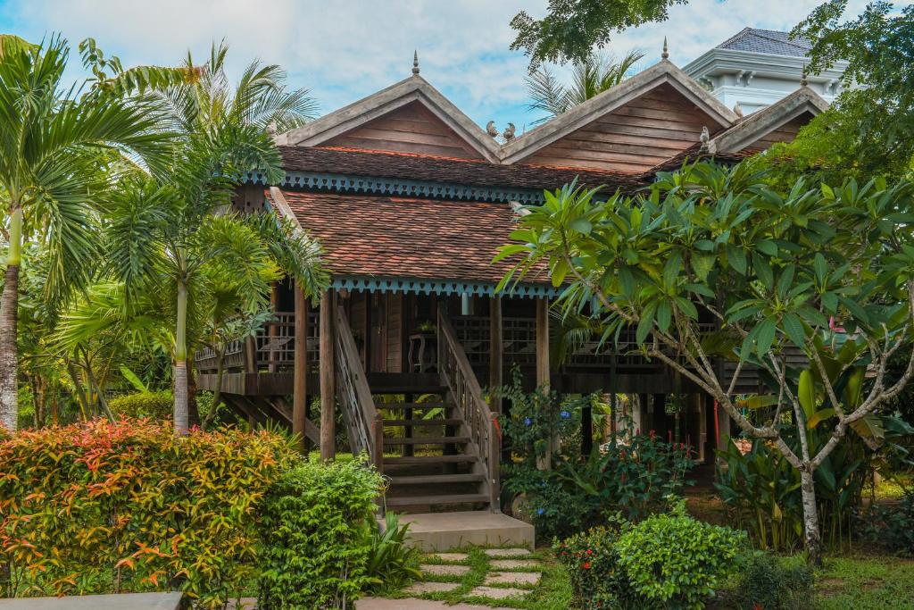 a wooden house with stairs and palm trees at Phum Khmer Lodge - Village Cambodian Lodge in Siem Reap