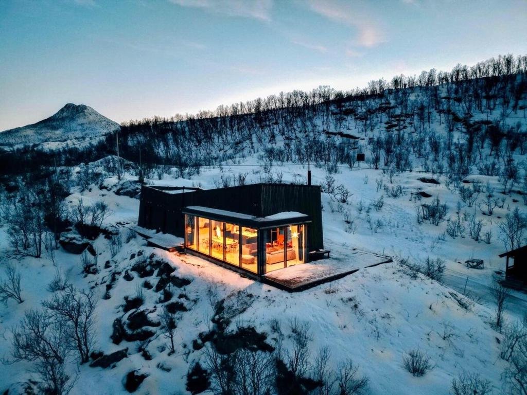 une petite cabine dans la neige éclairée dans l'établissement Senjavista, near nature, sea and mighty mountains, à Skaland