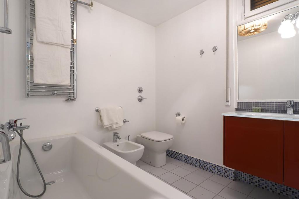 a bathroom with a tub and a toilet and a sink at HomNest I S.Ambrogio Elegant Apt in Milan