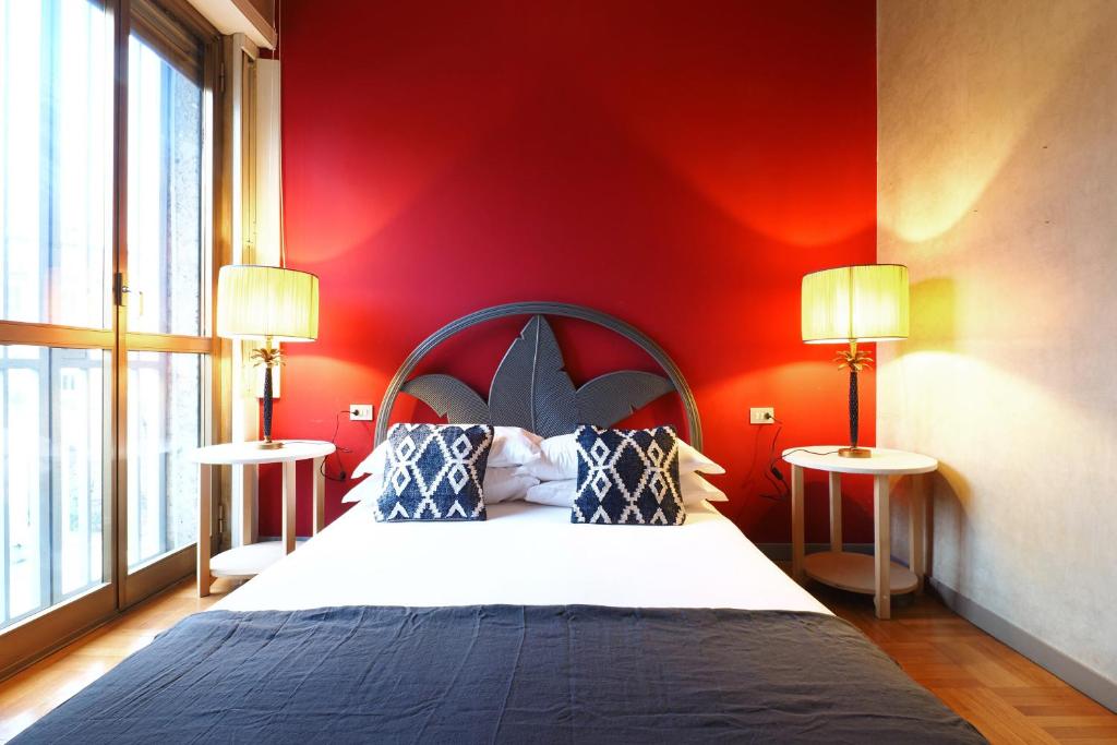 a bedroom with a bed with red walls and two lamps at HomNest I S.Ambrogio Elegant Apt in Milan