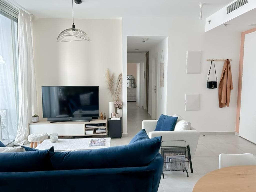 un soggiorno con divano blu e TV di Gindi Tower Apartments TLV a Tel Aviv