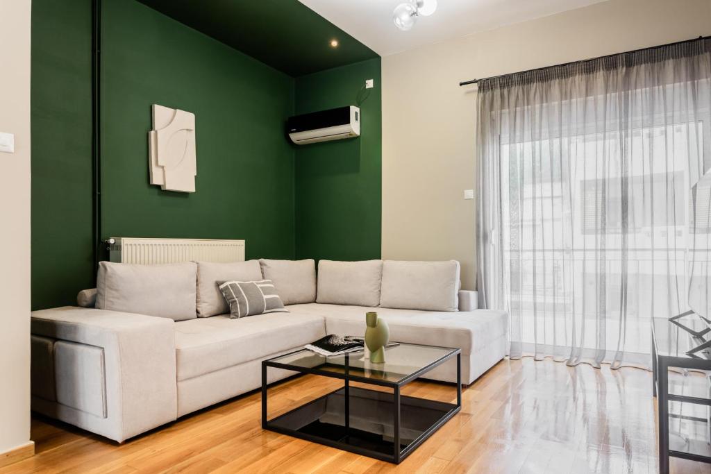 a living room with a white couch and a green wall at The Gate by Zoia Living in Athens