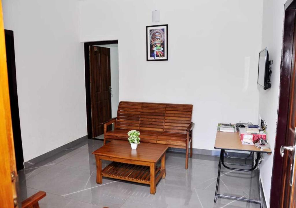 uma sala de estar com um banco e uma mesa em Whiteway Homestay em Kūmudi