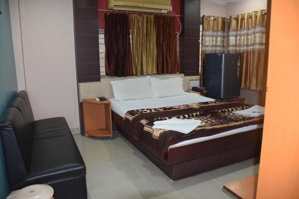 a small bedroom with a bed and a chair at Starline Hotel in Agartala