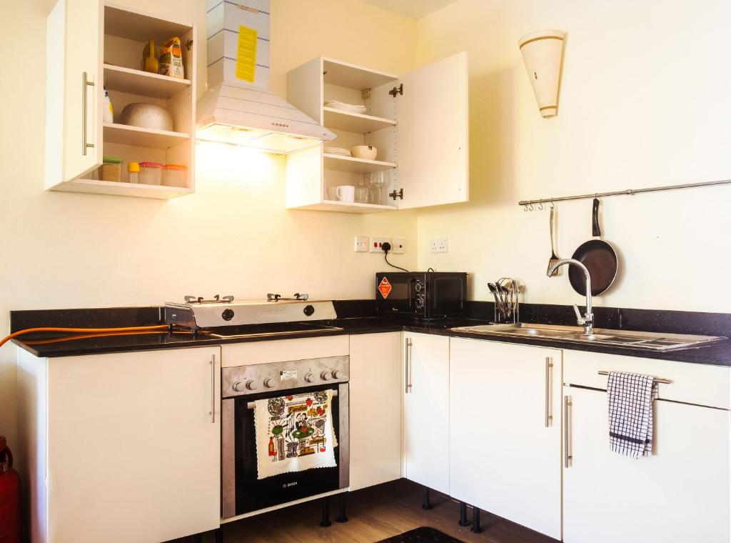 a kitchen with white cabinets and a stove at Harmony Homes Beachfront in Diani Beach