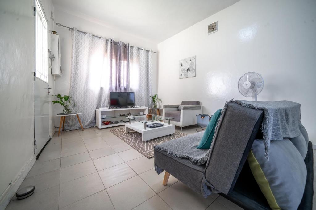 a white living room with a couch and a tv at Charmant Studio bien équipé in Dakar
