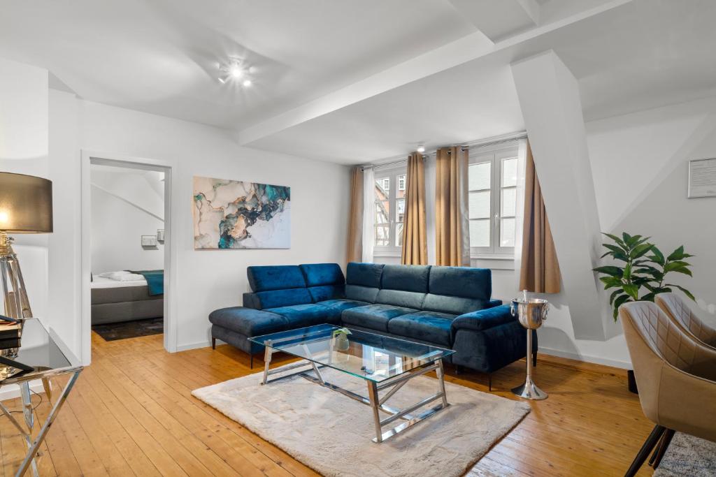 een woonkamer met een blauwe bank en een glazen tafel bij Traumhaft gelegene Altbau-Wohnung im Herzen von Weinheim in Weinheim