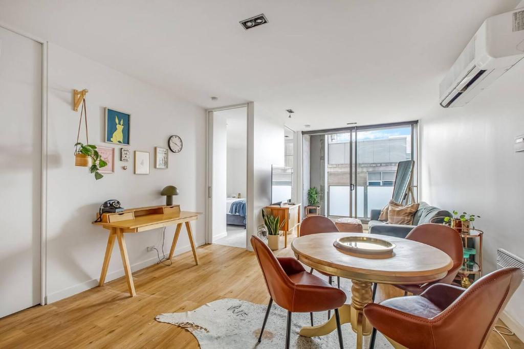 een woonkamer met een tafel en stoelen bij The Sweet Escape - Chic Apartment with Rooftop Pool in Melbourne