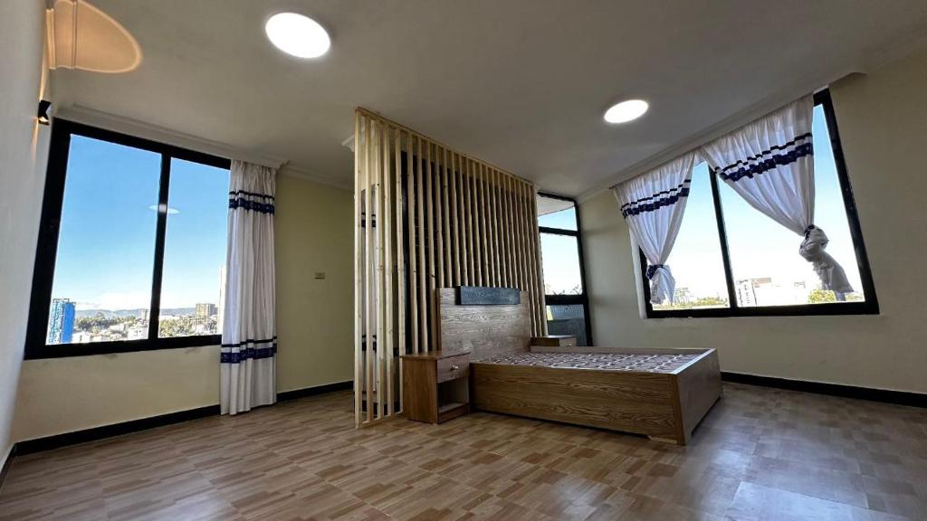 a large room with large windows and a bed in it at Annaye Apartment in Addis Ababa