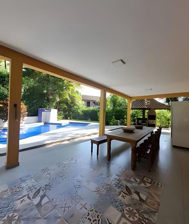 a dining room with a table and a pool at bwelcome - casa de praia com estilo único GH in Bertioga