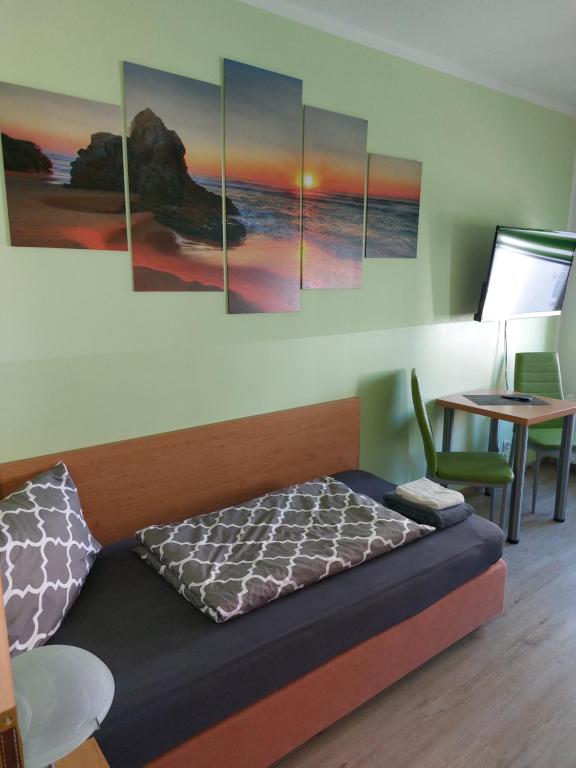 Zimmer mit einem Bett mit Gemälden an der Wand in der Unterkunft Ferienwohnung Holzhausen in Leipzig