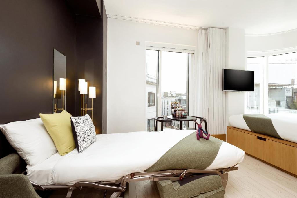 Wilde Aparthotels London Covent Garden في لندن: غرفة نوم بسرير كبير وتلفزيون