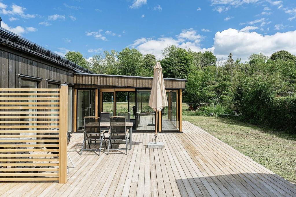 una terraza de madera con mesa y sombrilla en Very nice cottage near Borgholm, en Borgholm