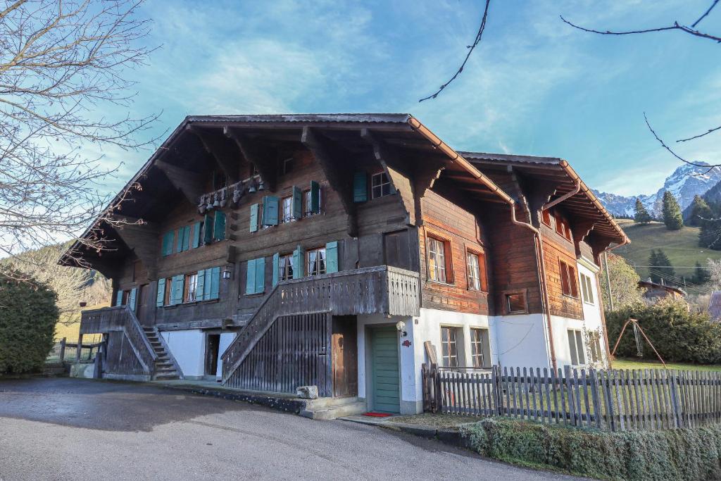 une grande maison en bois avec un escalier en face de celle-ci dans l'établissement Chalet Marie-José, à Château-d'Oex