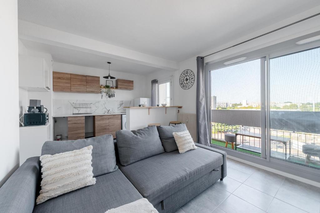 un salon avec un canapé et une grande fenêtre dans l'établissement Cosy T2, terrasse privée et Parking, à Toulouse