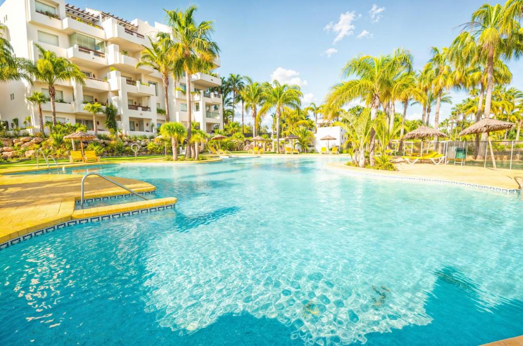 - une piscine dans un complexe avec des palmiers dans l'établissement Costalita Apartment - Pool by the Beach, à Estepona
