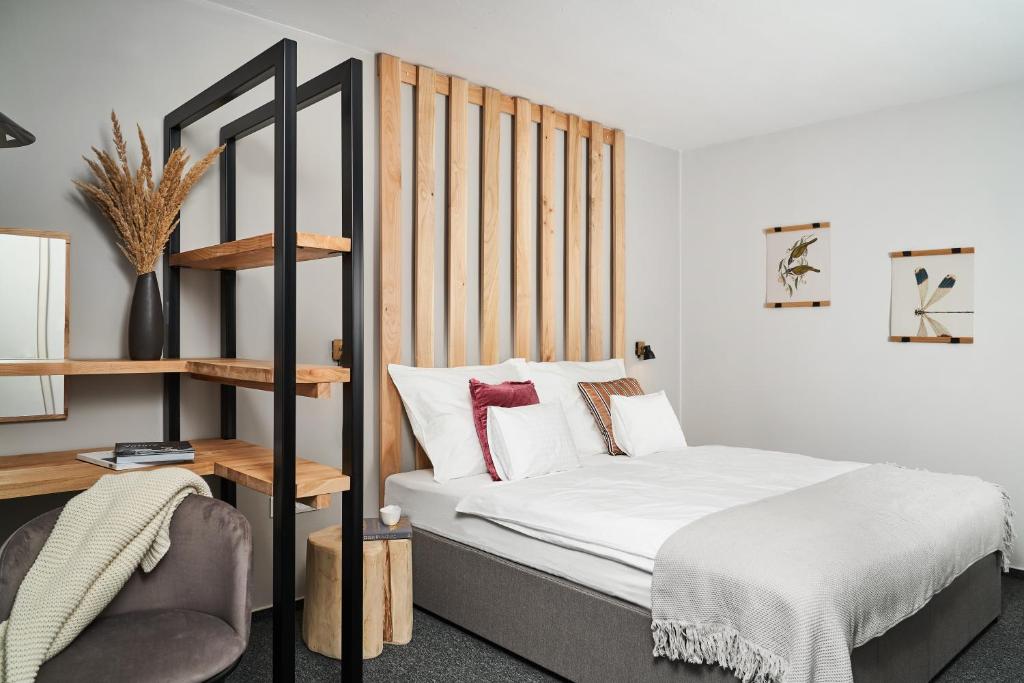 - une chambre avec un lit et une tête de lit en bois dans l'établissement Hotel Arborétum Harkány, à Harkány