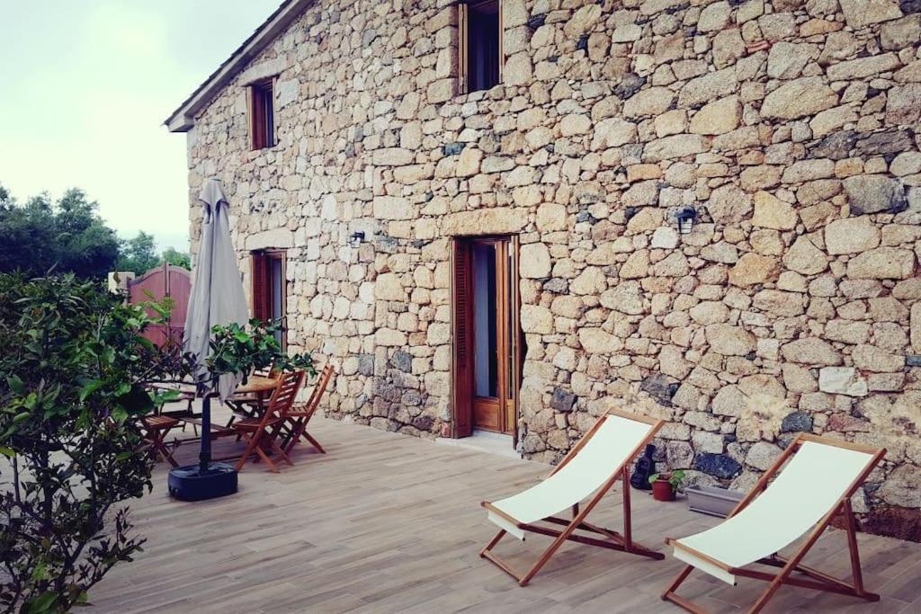 een patio met stoelen en een stenen gebouw bij Magnifique bergerie corse du 17eme Siècle à proximité des plages in Eccica-Suarella