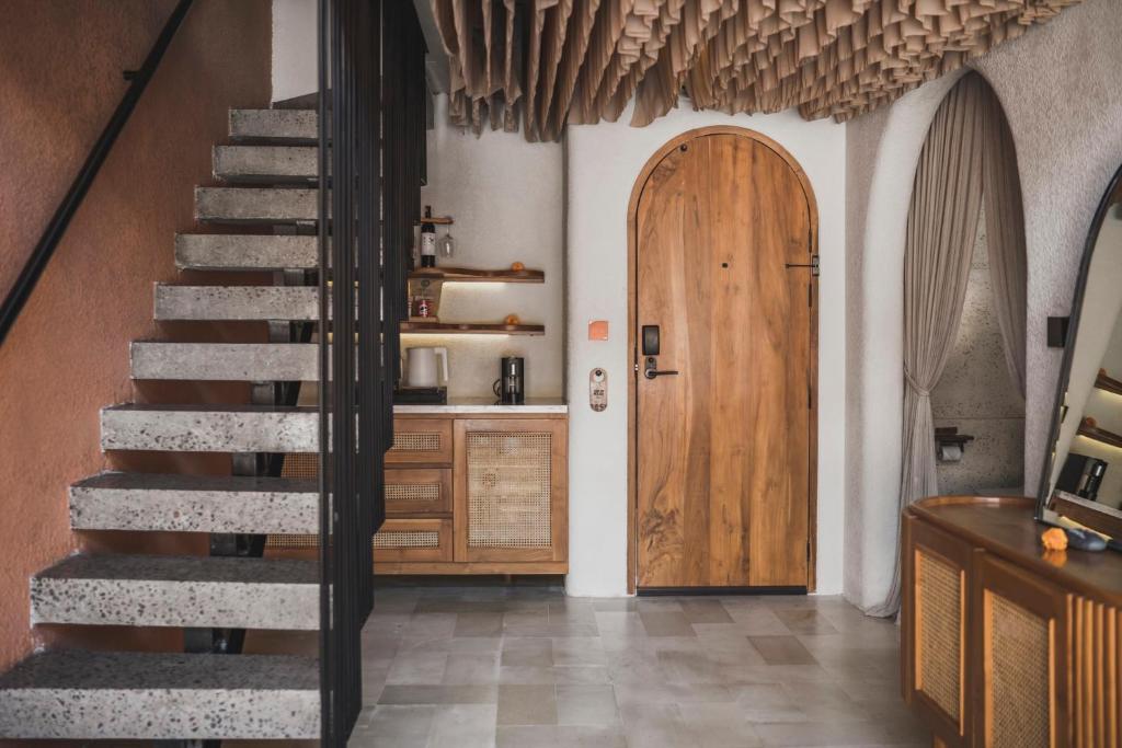 einen Flur mit einer Treppe und einer Holztür in der Unterkunft Cyrus Villa Seminyak by Ini Vie Hospitality in Seminyak