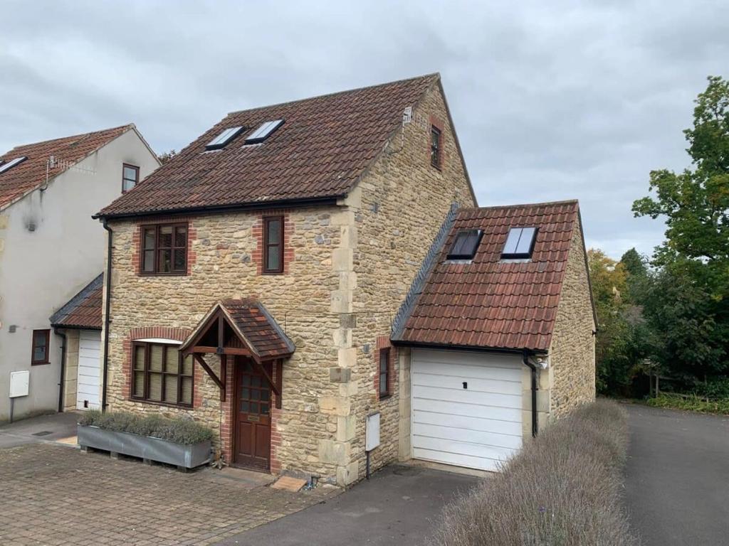 een groot bakstenen huis met een witte garage bij Sweet Modern Country Cottage with Garden in Frome