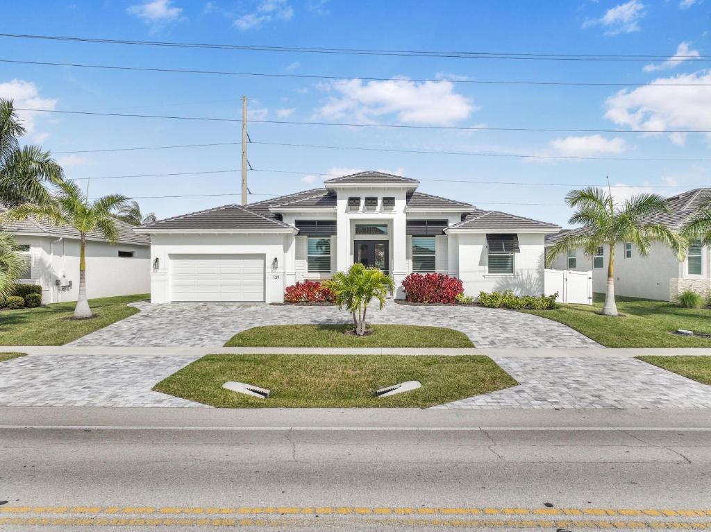 una casa blanca con palmeras delante en 2022 built home with pool/spa and walk to Mackle Park, en Marco Island