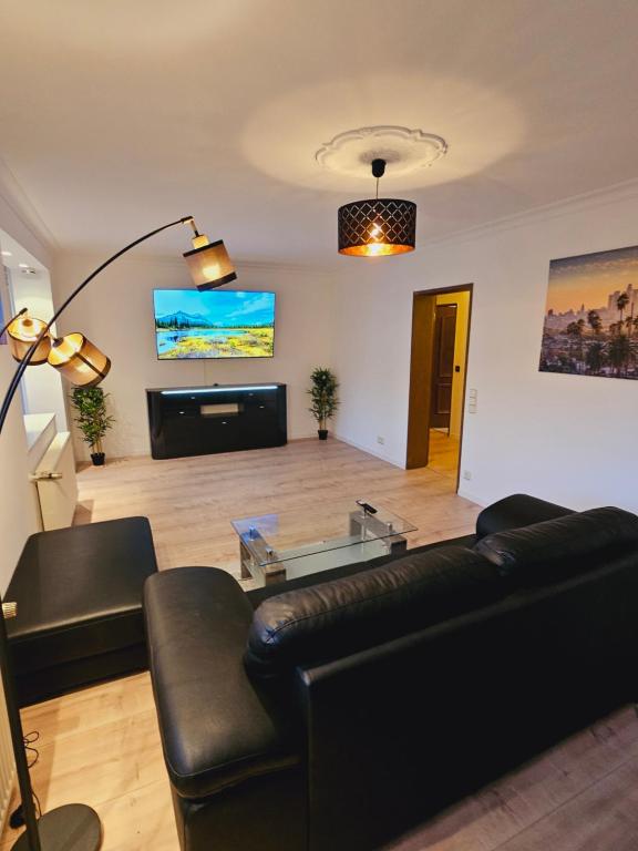 a living room with a black couch and a tv at B02 Schöne Apartments in Barsinghausen in Barsinghausen