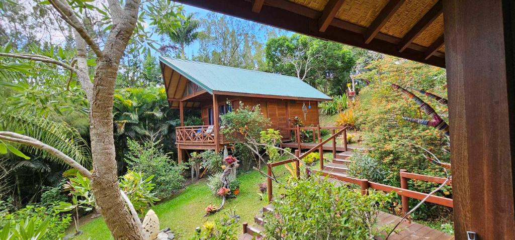 une petite cabane en bois dans un jardin avec une terrasse couverte dans l'établissement Oasis de Tendéa - Bali à Farino, à Farino
