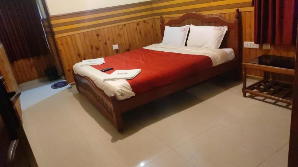 1 dormitorio con 1 cama con manta roja en FLGHR Pc Residency, en Kodaikanal