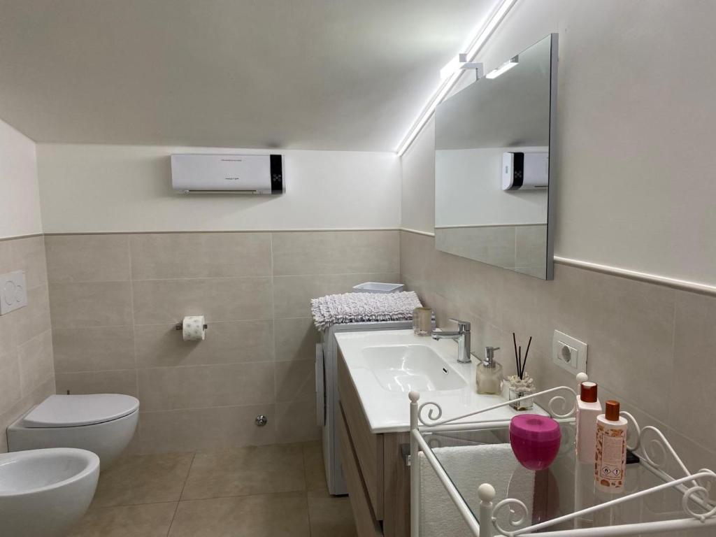 een badkamer met een wastafel, een toilet en een spiegel bij The Gods Brothers in Agerola