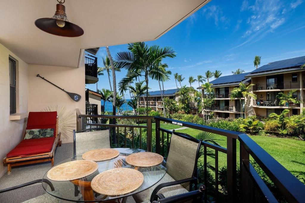 einen Balkon mit Tischen und Stühlen und Meerblick in der Unterkunft Kona Makai 3-203 in Kailua-Kona