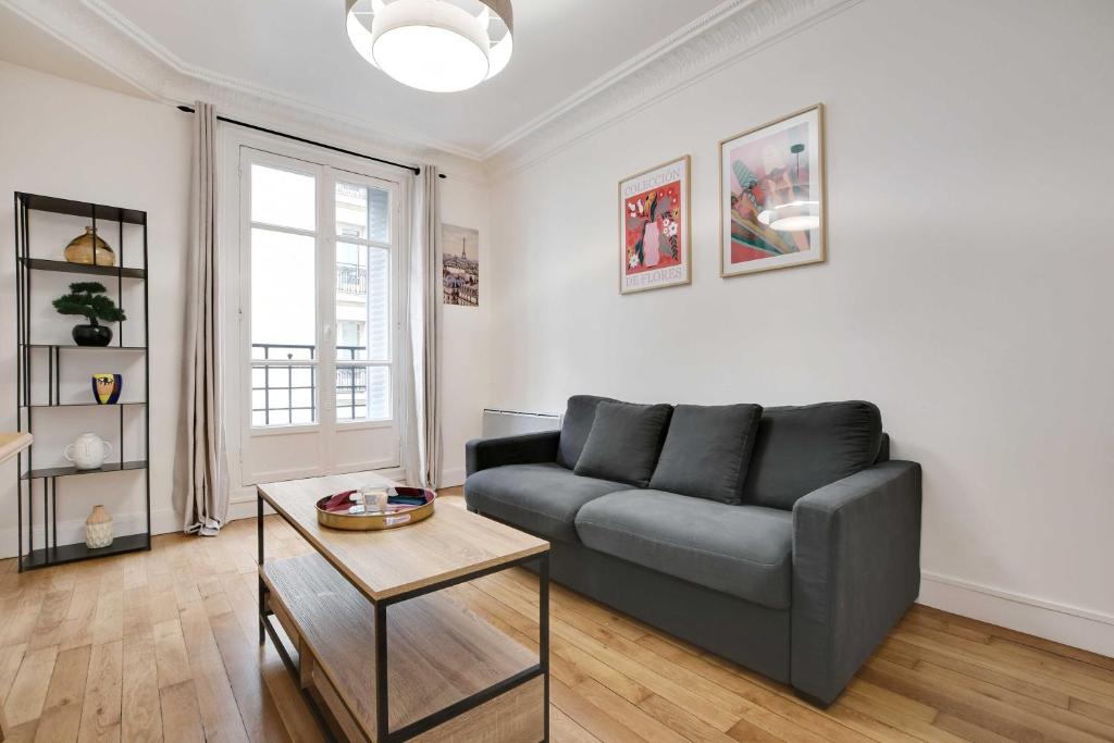 ein Wohnzimmer mit einem Sofa und einem Tisch in der Unterkunft Cosy 2P flat Parc des Princes Exelmans in Paris