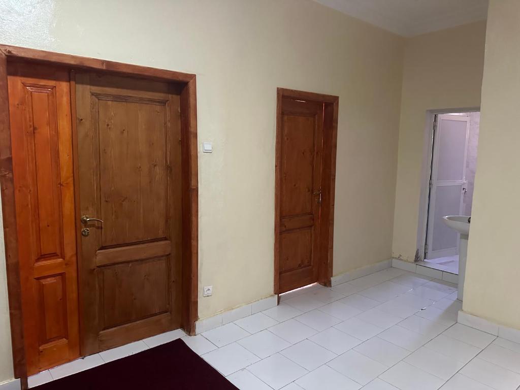an empty room with two wooden doors and a sink at Darius Adefon in Nouakchott
