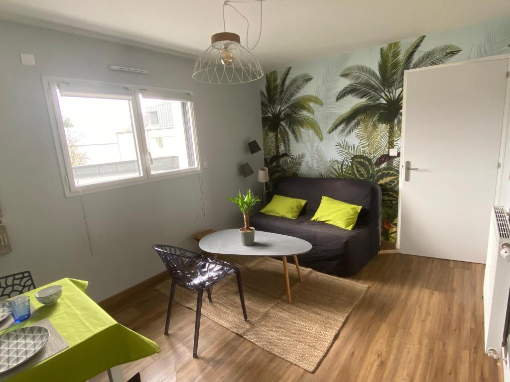 ein Wohnzimmer mit einem Sofa und einem Tisch in der Unterkunft Apt 2 3 personnes acces jardin 15 min de la mer in Brech