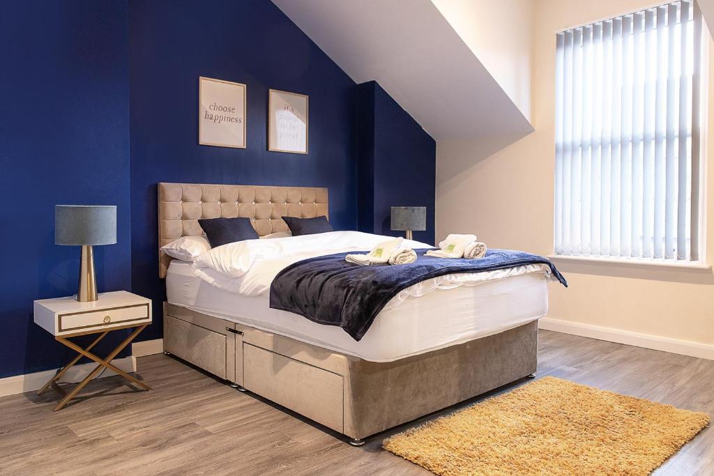 een slaapkamer met een groot bed met blauwe muren bij Station Apartment - 3 bedroom, five minutes from Harrogate Convention Centre in Harrogate